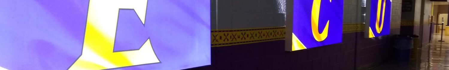Illuminated E C U letters displayed along a stadium concourse hallway